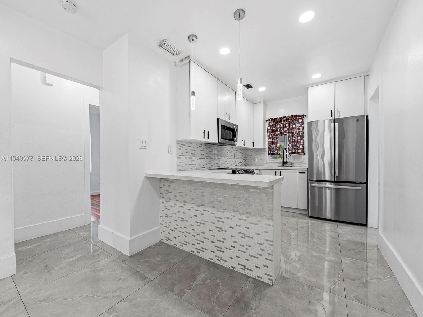 1230 Northwest 35th Street Miami, FL 33142 - Photo 8 of 36 a kitchen with a refrigerator a sink and white cabinets