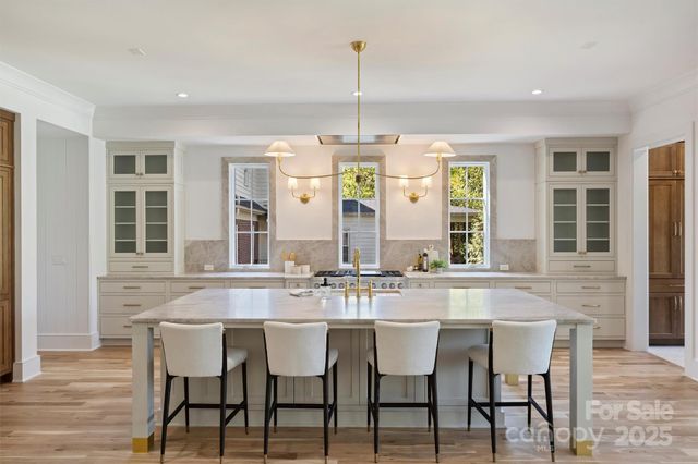 a large white kitchen with lots of counter space and view of living room