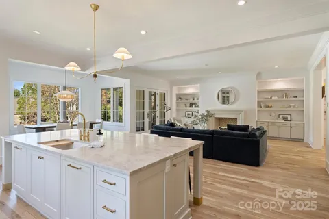 a large kitchen with granite countertop a stove a sink a refrigerator and a dining table with wooden floor
