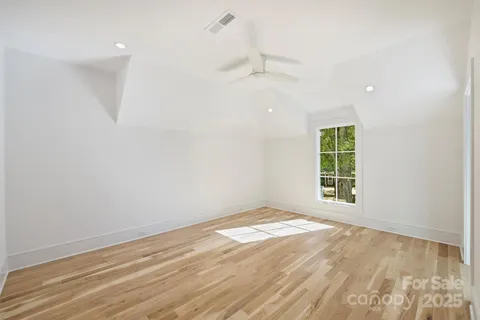 an empty room with wooden floor cabinet and windows