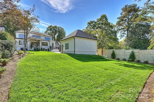 a white house that has a big yard with large trees