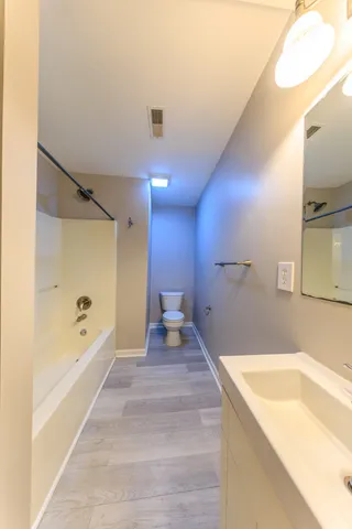 a spacious bathroom with a tub sink and mirror