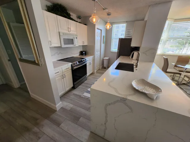 a kitchen with stainless steel appliances a dining table chairs stove refrigerator and wooden floor