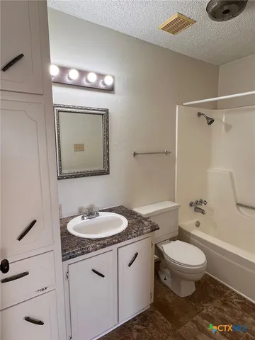 a bathroom with a granite countertop toilet sink and mirror