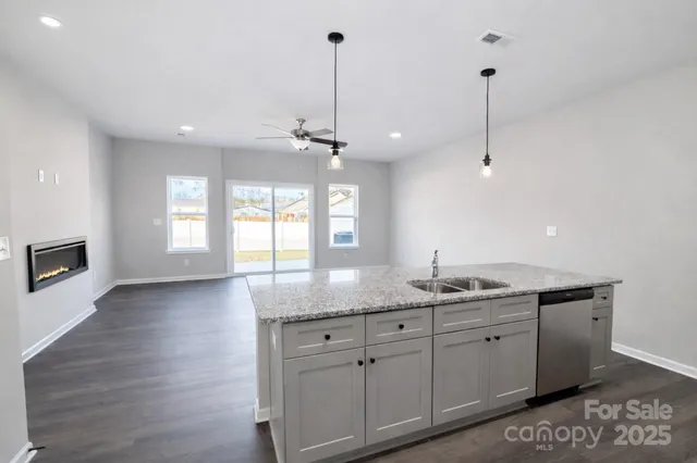 a kitchen with granite countertop a sink cabinets and wooden floor