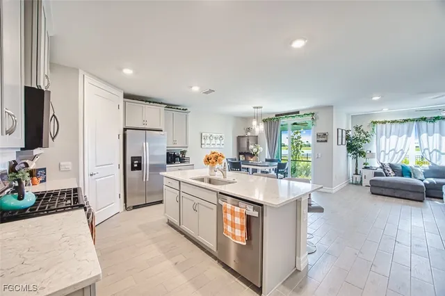 a large white kitchen with a refrigerator a stove a microwave oven with a dining table and chairs