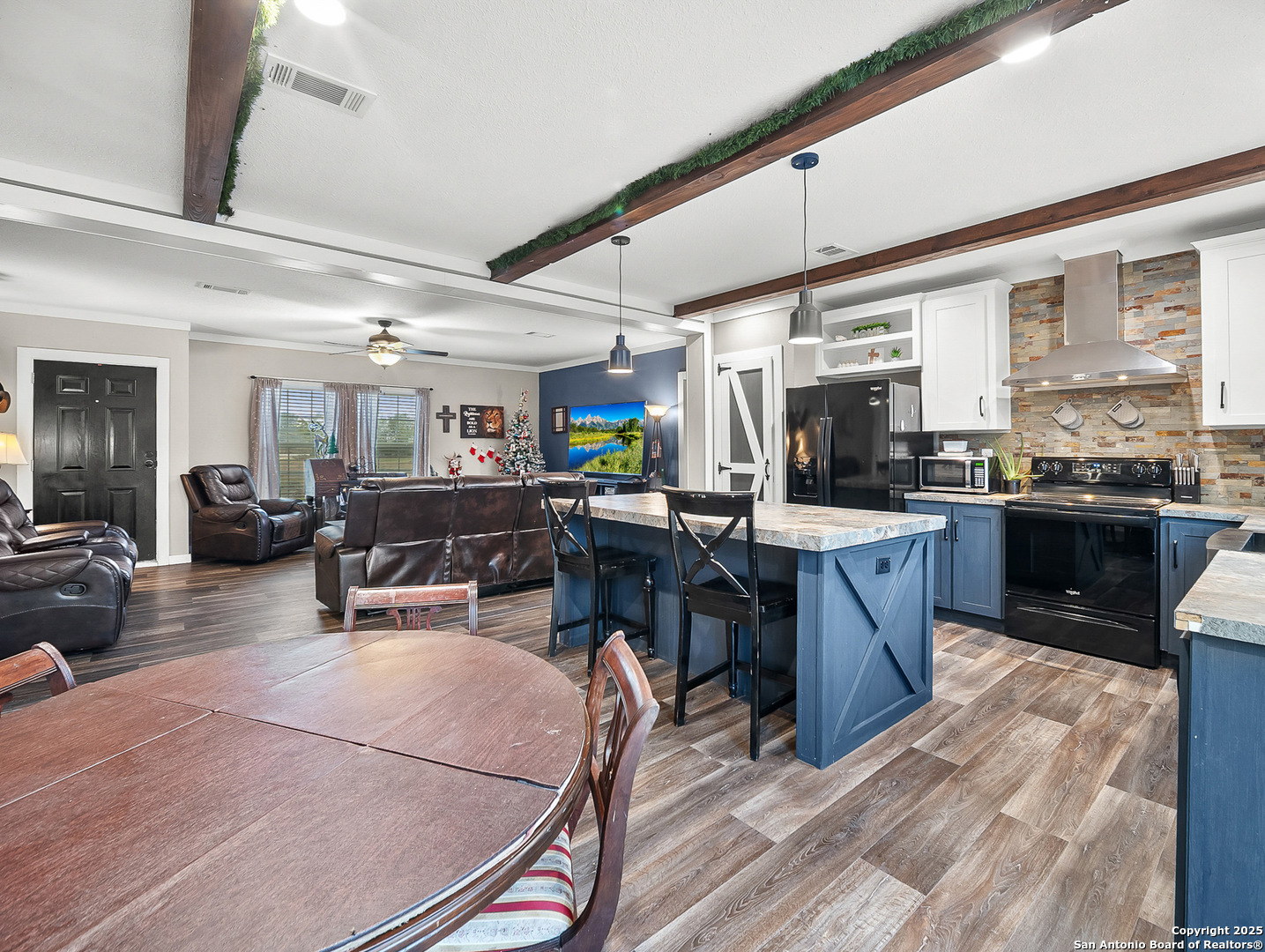 3809 Callihan Road Luling, TX 78648 - Photo 11 of 38 a kitchen with stainless steel appliances kitchen island granite countertop a refrigerator a stove a sink a dining table and chairs with wooden floor