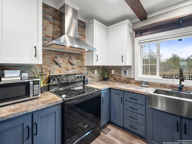 a kitchen with granite countertop stainless steel appliances a stove sink and cabinets