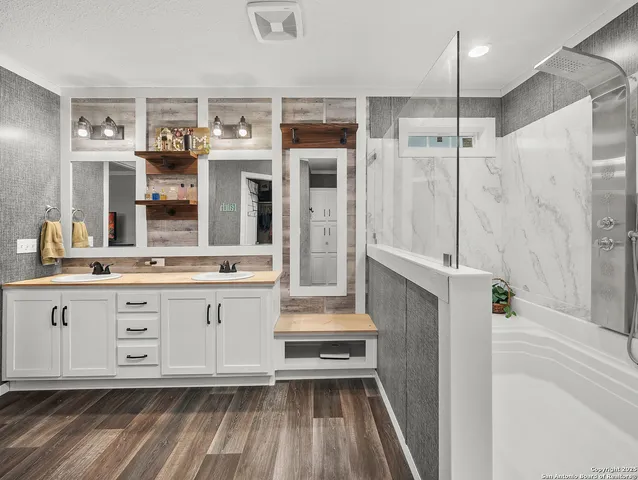 a bathroom with a double vanity sink a mirror and a shower