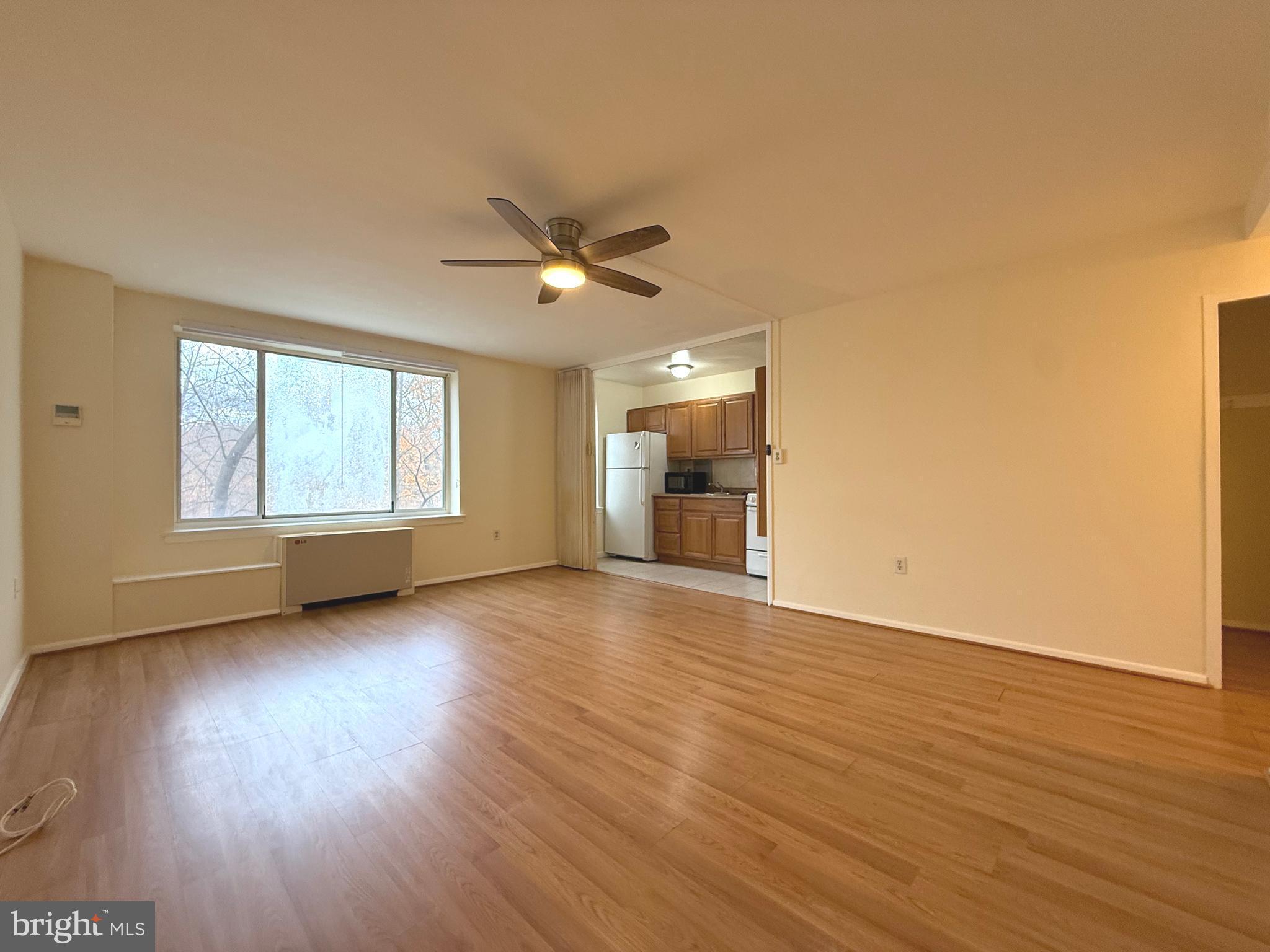 4100 W Street Northwest, Unit 303 Washington, DC 20007 - Photo 3 of 15 a view of a livingroom with wooden floor a ceiling fan and windows