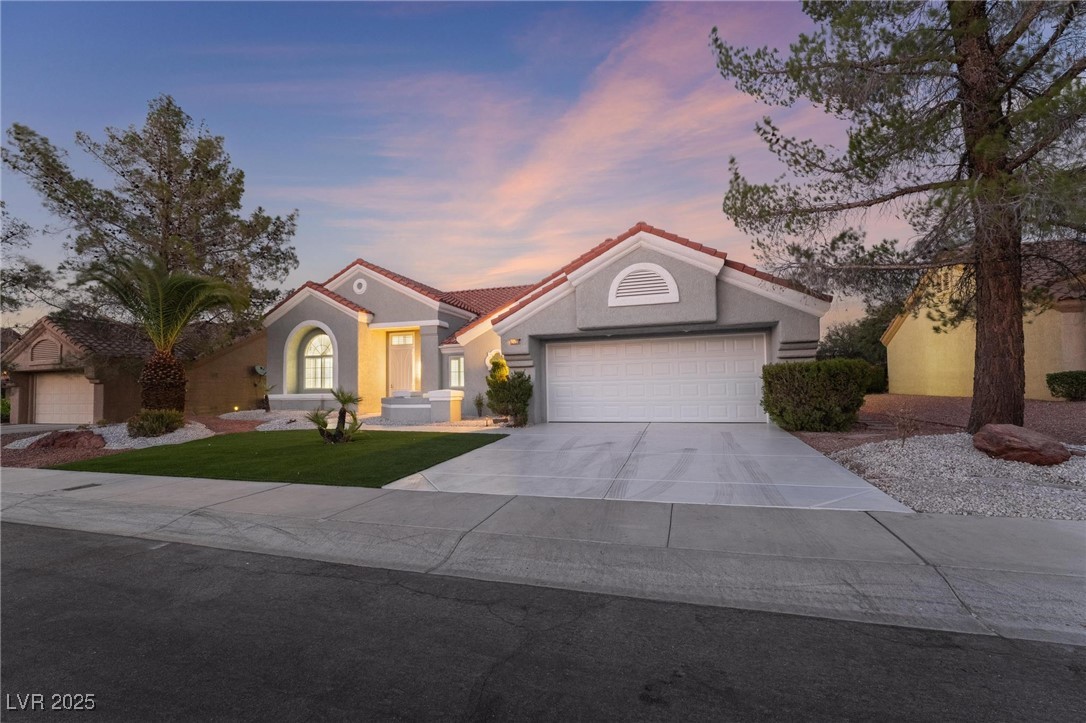 Mediterranean / spanish home with concrete driveway, a garage, a front yard, a tile roof, and stucco siding