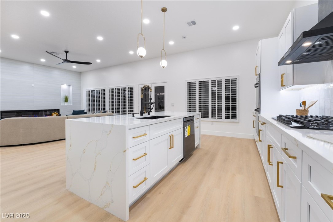 2528 Sunup Drive Las Vegas, NV 89134 - Photo 24 of 24 Kitchen featuring white cabinetry, light stone counters, open floor plan, wall chimney exhaust hood, and recessed lighting
