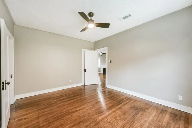 a view of empty room with wooden floor and fan