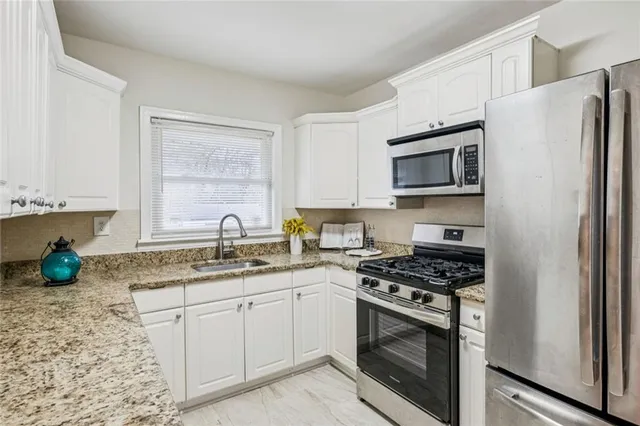 a kitchen with granite countertop a sink and a white wooden cabinets