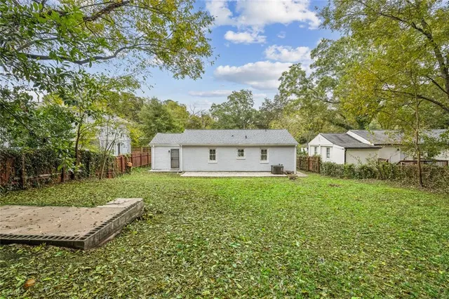 a backyard of a house with lots of plants and large tree