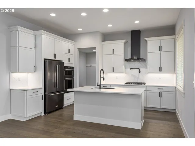 a kitchen with stainless steel appliances kitchen island a refrigerator sink and cabinets
