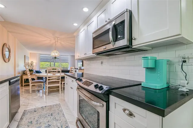 a open kitchen with stainless steel appliances granite countertop a stove top oven microwave and cabinets