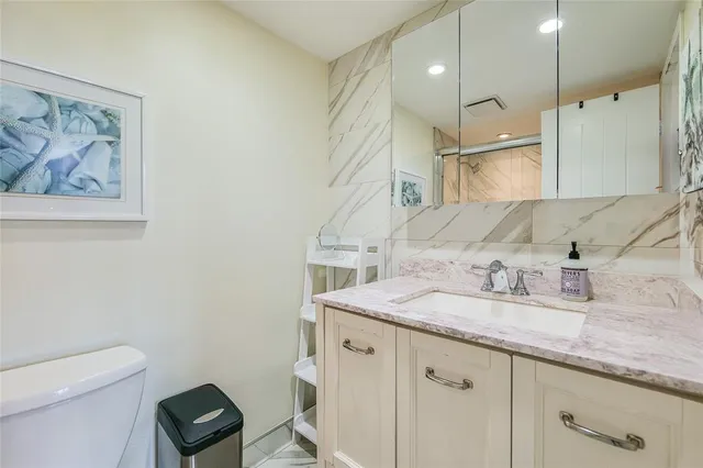 a bathroom with a granite countertop sink a toilet a large mirror and shower