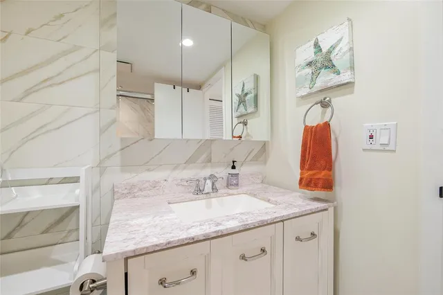 a bathroom with a granite countertop sink a large mirror and shower
