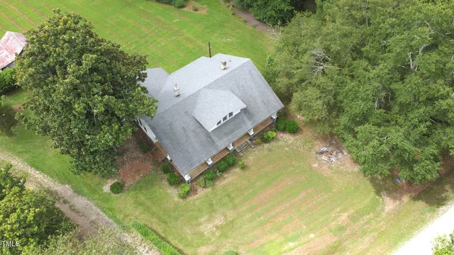 an aerial view of a house with a yard and trees all around