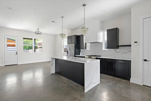 a kitchen with stainless steel appliances granite countertop a stove a sink and a refrigerator