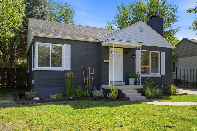 1187 East Ridgedale Circle Millcreek, UT 84106 - Photo 2 of 49 Charcoal-painted brick exterior with white trim, featuring a covered front porch, white front door, and a prominent chimney