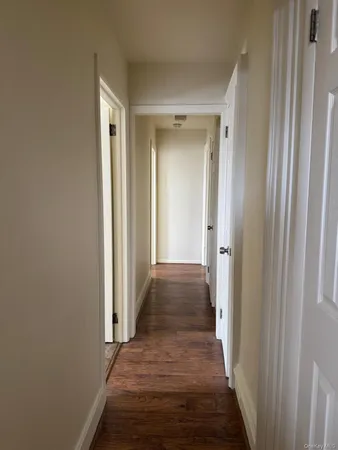 a view of a hallway with wooden floor and a bathroom