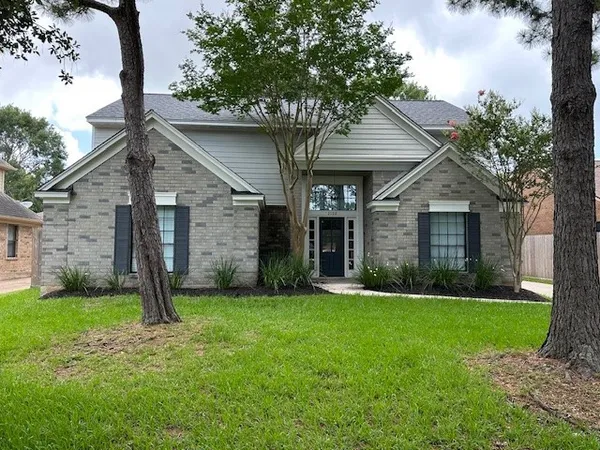front view of a house with a yard and an trees