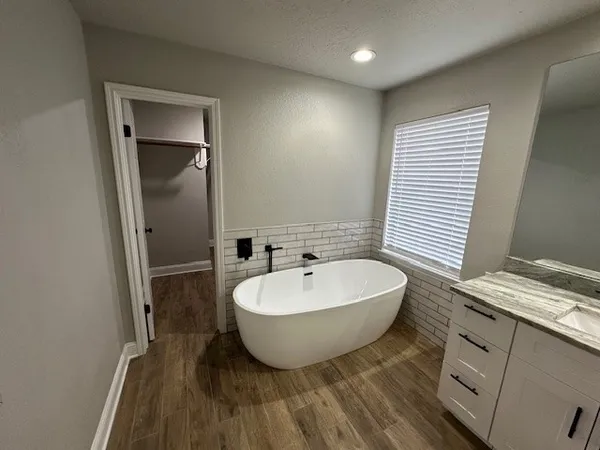 a spacious bathroom with a double vanity sink a mirror and a bathtub
