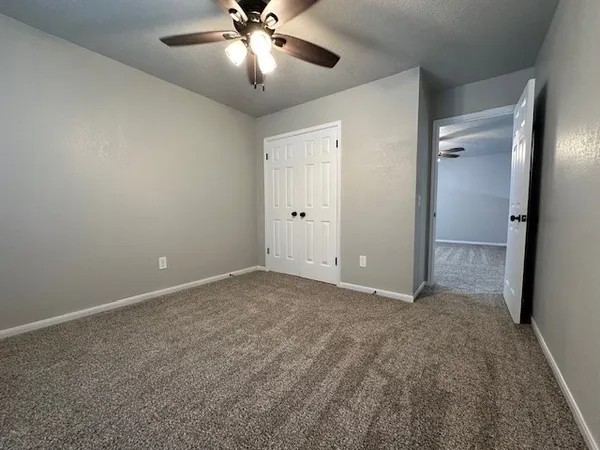 an empty room with a chandelier fan and closet area