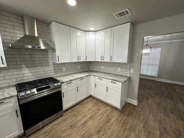 a kitchen with granite countertop cabinets stainless steel appliances and wooden floor