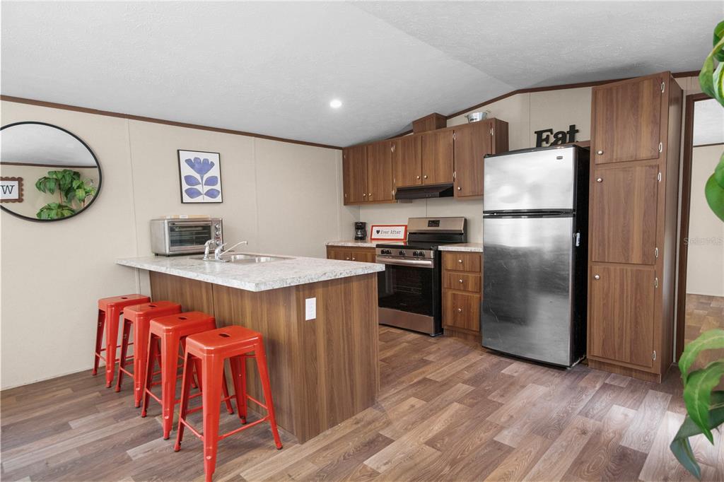 16770 Southwest 60th Place Ocala, FL 34481 - Photo 9 of 26 a kitchen with stainless steel appliances granite countertop a refrigerator a stove a sink and a dining table with wooden floor