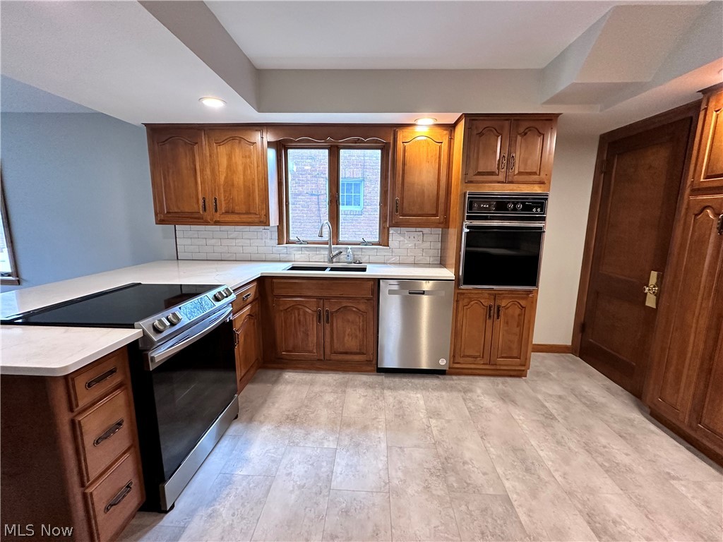 910 Cambridge Road Coshocton, OH 43812 - Photo 10 of 30 Kitchen featuring tasteful backsplash, a raised ceiling, kitchen peninsula, stainless steel appliances, and sink