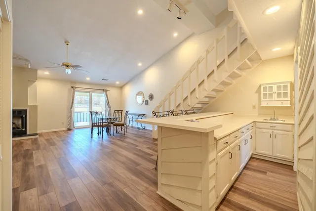 a large white kitchen with wooden floor and a sink
