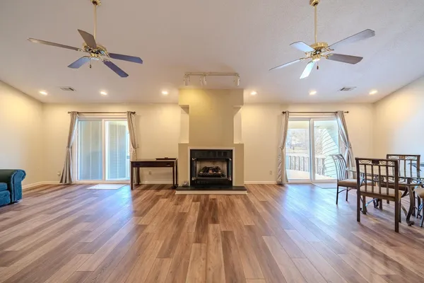 a view of a livingroom with a fireplace a ceiling fan and wooden floor