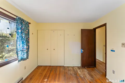 a view of hallway with window and wooden floor