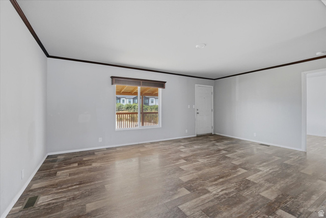 433 North 750 West Logan, UT 84321 - Photo 5 of 40 Spacious living area featuring wood-finish flooring, light gray walls, a window with a wood-toned valance, and a white entry door