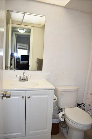 a bathroom with a granite countertop toilet sink and mirror