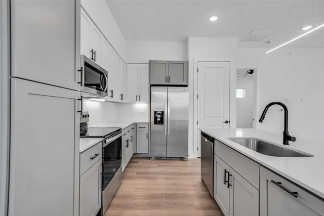 a kitchen with stainless steel appliances granite countertop a sink and a refrigerator