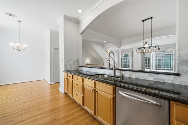 a kitchen with stainless steel appliances granite countertop a sink a stove and a wooden floors