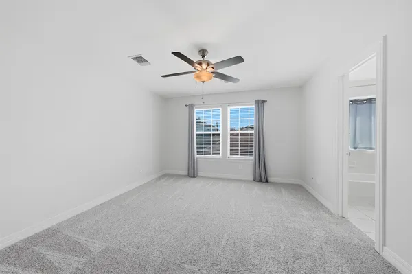 an empty room with chandelier fan and windows