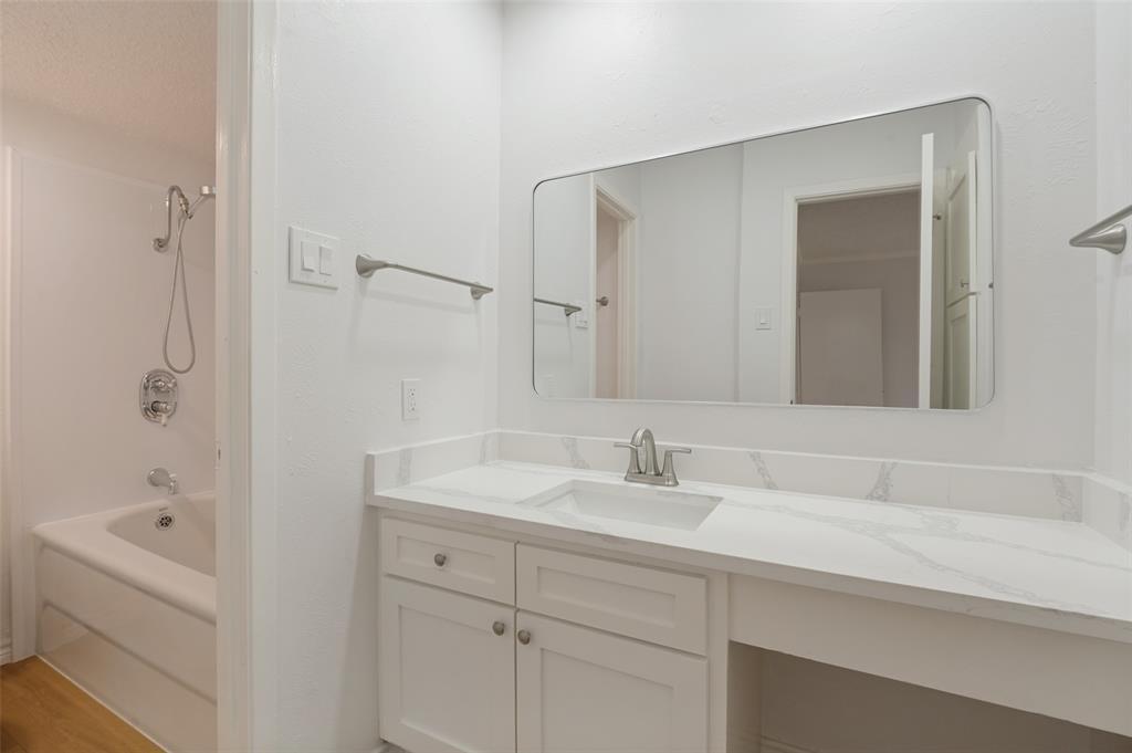 5300 Keller Springs Road, Unit 2042 Dallas, TX 75248 - Photo 23 of 28 Bathroom vanity with a white countertop and integrated sink, brushed nickel faucet, and a large rectangular mirror