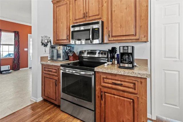 a kitchen with stainless steel appliances granite countertop a stove refrigerator a sink dishwasher and wooden cabinets with wooden floor