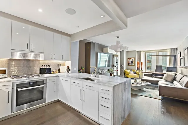 a open kitchen with stainless steel appliances kitchen island granite countertop a stove and white cabinets