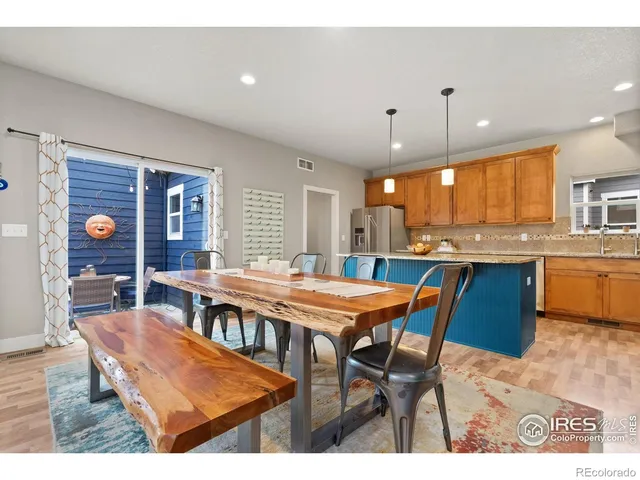 a kitchen with stainless steel appliances kitchen island granite countertop a table chairs sink and cabinets
