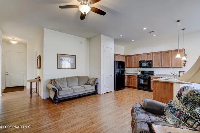 a living room with furniture kitchen view and a wooden floor