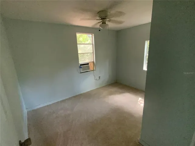 an empty room with windows and fan
