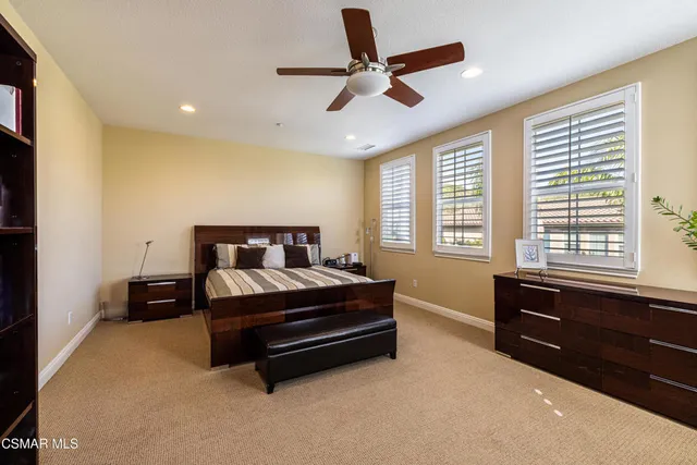 a spacious bedroom with a bed and a dresser next to a window
