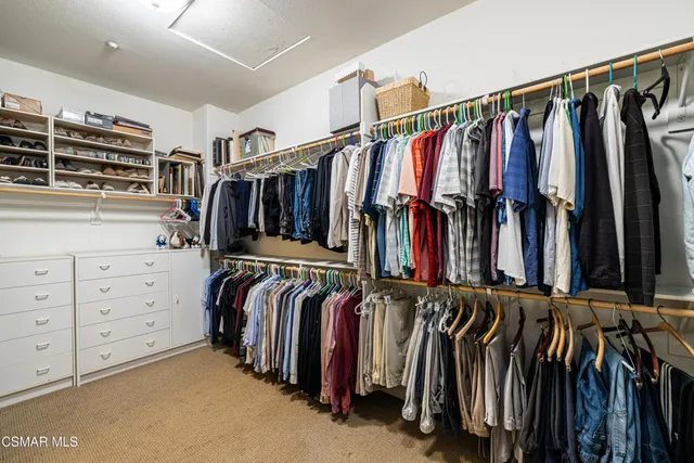 a view of walk in closet with clothes and shoes