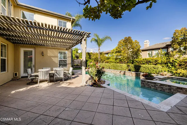 a view of a patio with dining table and chairs with plants and a barbeque grill